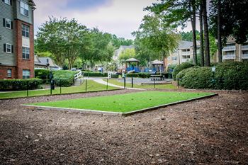 a park with grass and a playground in front of apartment buildings